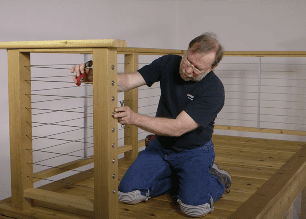 person installing cable railing for wood frame