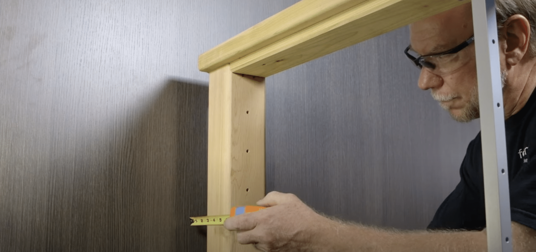 man measuring wood frame